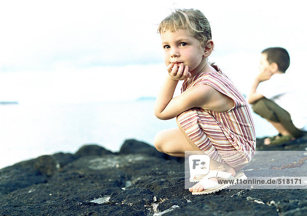 Zwei Kinder kauern auf dem Felsen