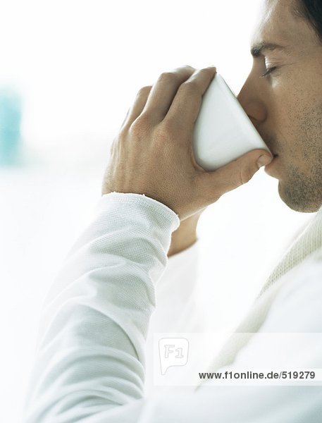 Man drinking from cup  eyes closed