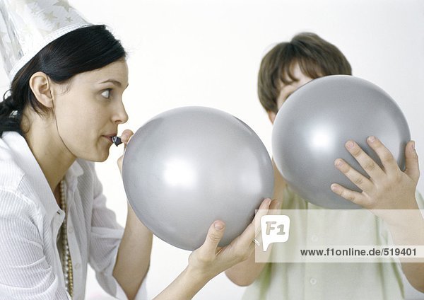 Woman and boy blowing up silver balloons