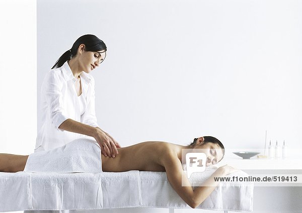 Frau massiert zweite Frau auf Massagetisch