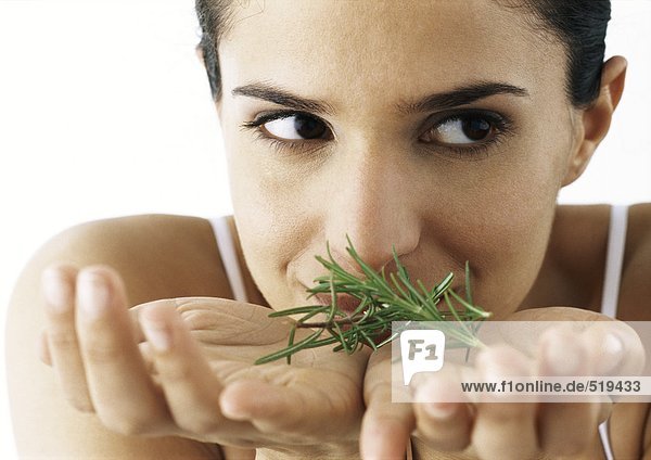Woman holding sprigs of rosemary in palms  looking to the side  close-up