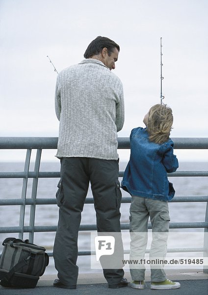 Man and son fishing on pier  rear view