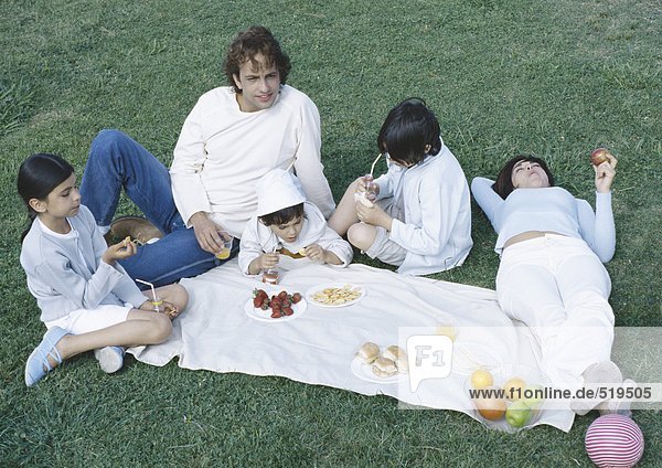 Eltern mit Jungen und Mädchen beim Picknick auf dem Rasen