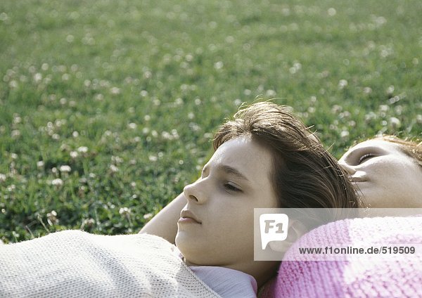 Mädchen und Mutter auf Gras liegend