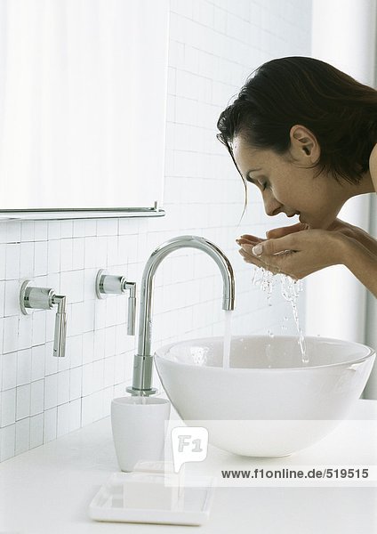 Frau beugt sich über die Spüle  Gesicht waschend