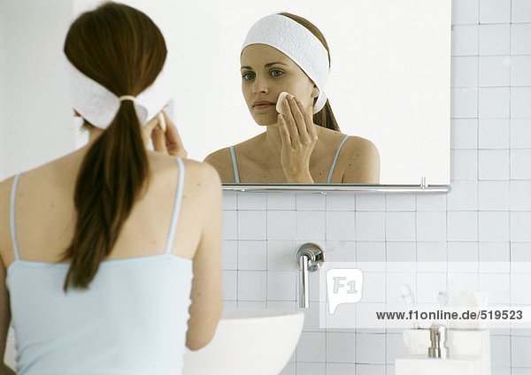 Frau wäscht Gesicht vor dem Spiegel