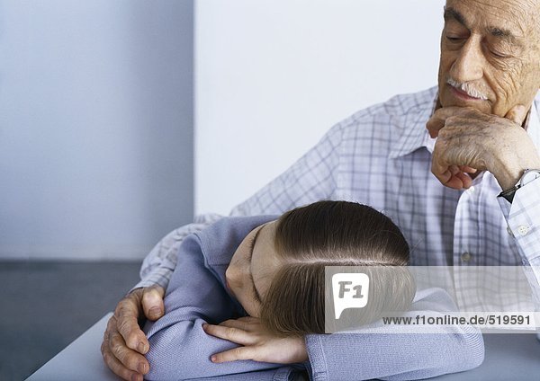Großvater tröstende Enkelin  der Kopf des Mädchens ruht auf den Armen.