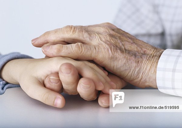 Großvaters Hände  die die Hand des Kindes umklammern.