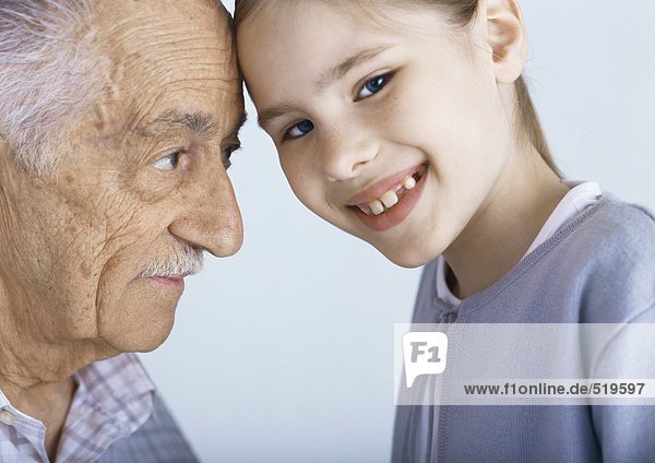 Großvater und Enkelin berühren die Stirn  Portrait