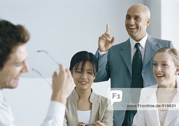 Colleagues having meeting  smiling  one man pointing finger