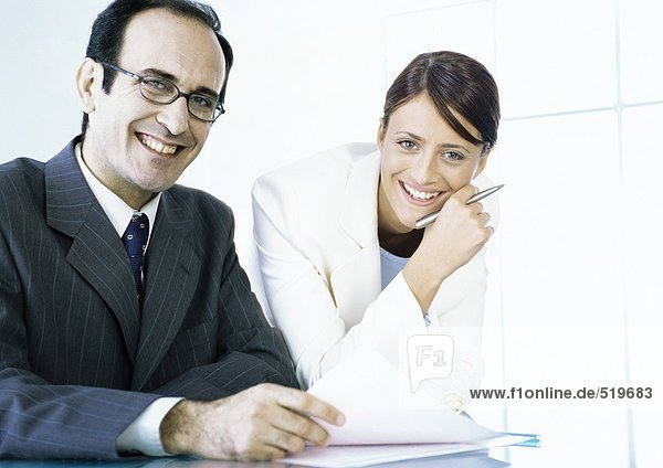 Businessman and businesswoman with documents smiling at camera