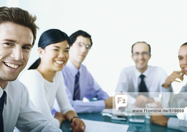 Businesspeople sitting around table  smiling