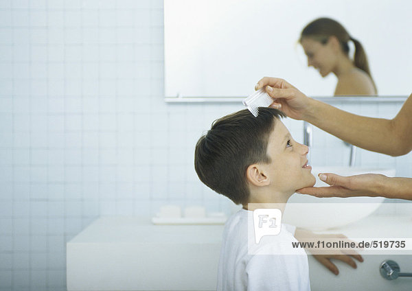 Woman combing boy's hair