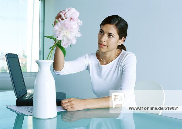 Frau am Schreibtisch arrangiert Blume in Vase