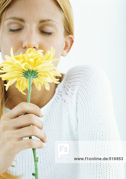 Frau riecht Blume mit geschlossenen Augen