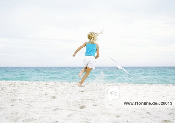 Mädchen läuft der Möwe am Strand hinterher.