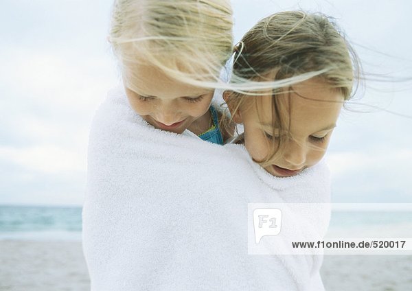 Zwei Mädchen in ein Handtuch gewickelt am Strand