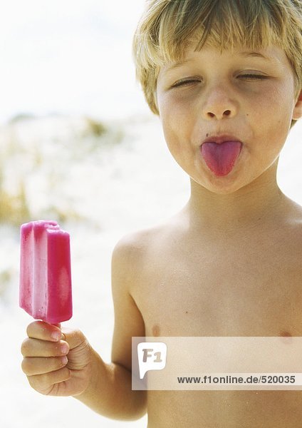 Little boy with popsicle  sticking tongue out with eyes closed