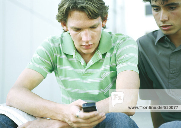 Two students sitting side by side  looking at cell phone