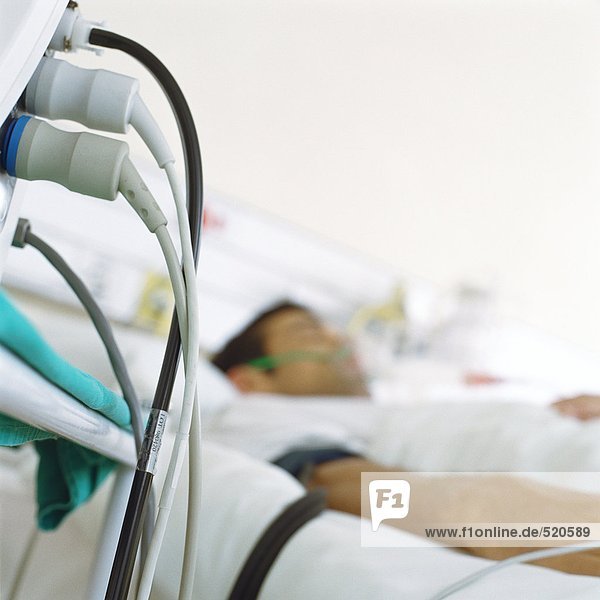 Patient im Krankenhausbett und Kabel vom Monitor