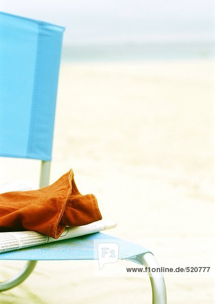 Zeitung und Kleidungsstück auf Strandkorb