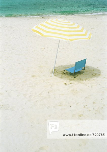 Sonnenschirm und Klappstuhl am Strand