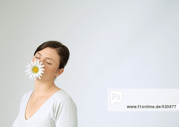 Junge Frau mit Blume im Mund und geschlossenen Augen  Portrait