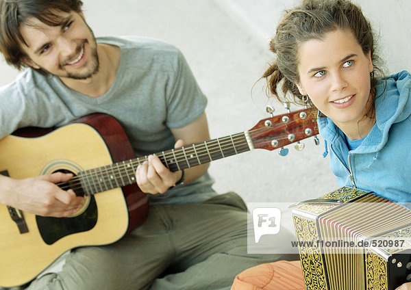Young man playing guitar  young woman playing accordion