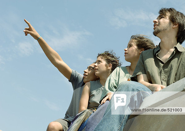 Vier junge Freunde stehen und schauen in den Himmel.