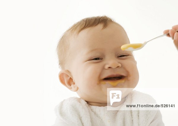 Lächelndes Baby wird mit Babynahrung gefüttert