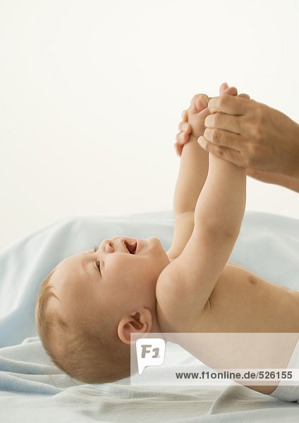 Elternteil hebt das Baby mit den Händen an.