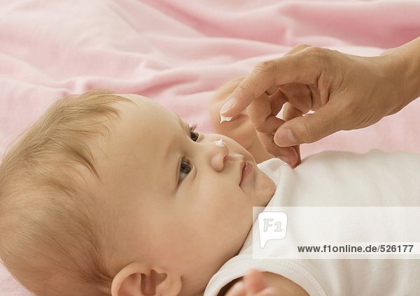 Baby mit einem Tupfer Lotion auf der Nase