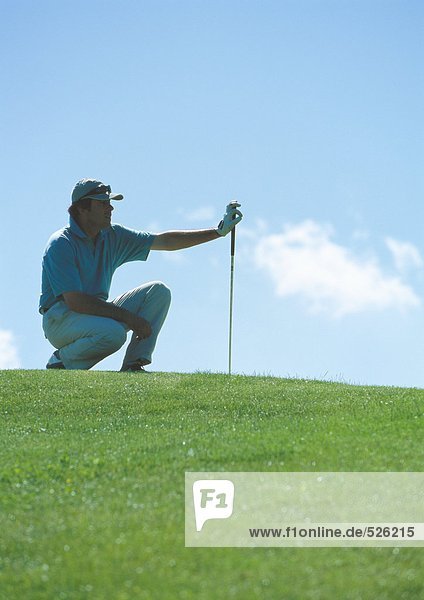 Golfer squatting on green