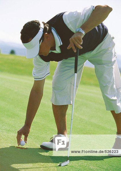 Golfer picking up golf ball
