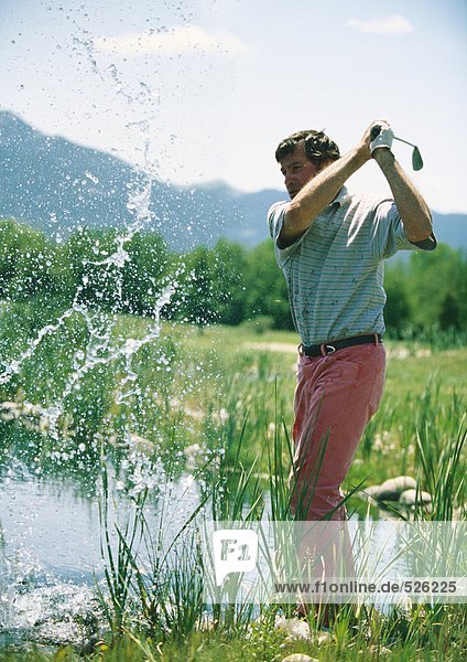 Golfer swinging in water