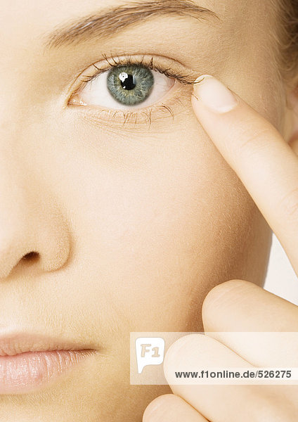 Frauengesicht mit Finger neben dem Auge  extreme Nahaufnahme