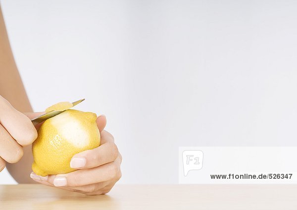 Frauenhände schälen Zitrone