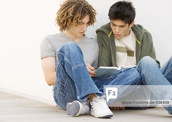 Zwei Studenten sitzen auf dem Boden und lernen zusammen.