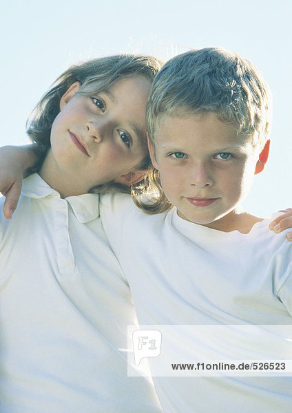 Boy and girl standing with arms around each other's shoulders  portrait