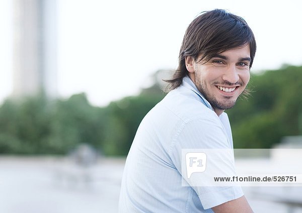 Junger Mann lächelt im Stadtpark  Portrait