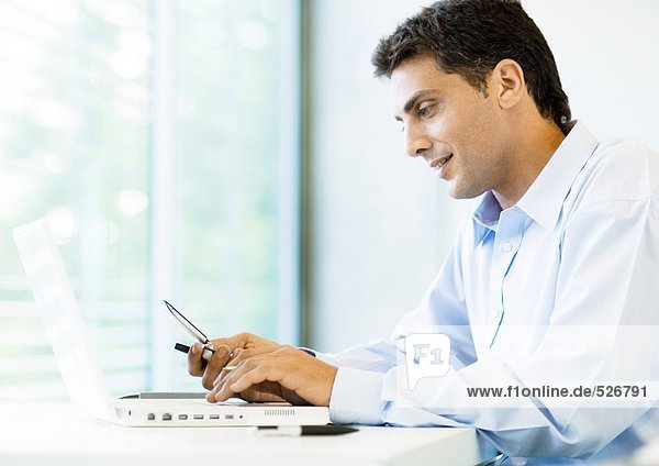 Businessman using cell phone and laptop