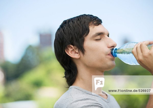 Junger Mann trinkt Wasser aus der Flasche