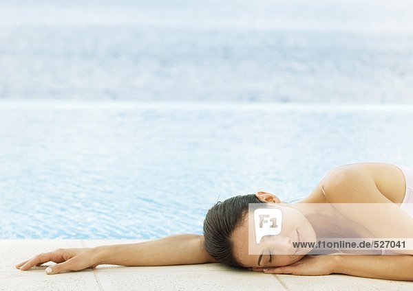 Frau schlafend auf dem Boden am Wasserrand