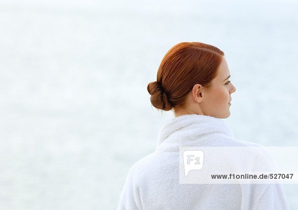 Frau im Bademantel  Blick aufs Meer  Rückansicht