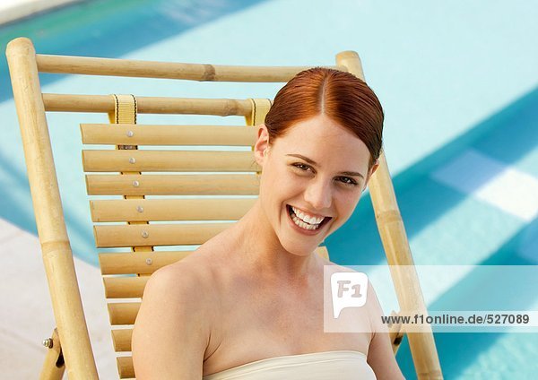Frau im Liegestuhl lächelnd  Pool im Hintergrund