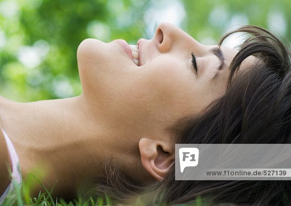 Junge Frau im Gras liegend mit geschlossenen Augen