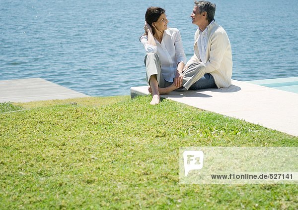 Mid-adult couple sitting by edge of water