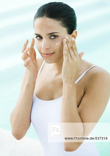 Woman applying sunscreen to face