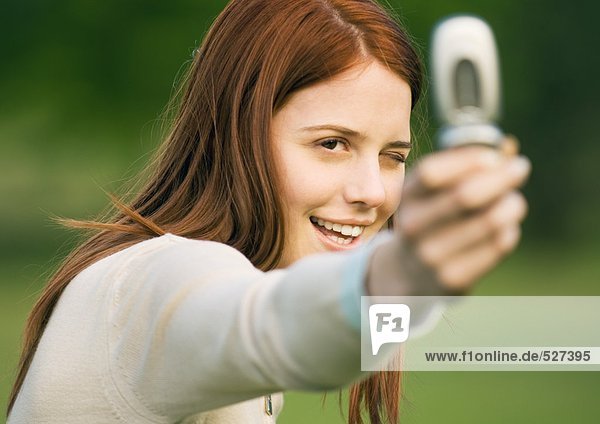 Junge Frau hält Kamera-Handy hoch  fotografiert
