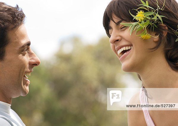 Young couple laughing  woman wearing flowers behind ear